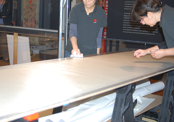 The first team of conservators applies a paste to the backing paper.