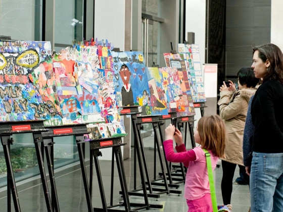 Young visitor holds up smartphone to take a photograph of row of artwork on easels Young visitor holds up smartphone to take a photograph of row of artwork on easels