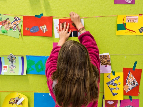Young visitor hanging up collage on wall