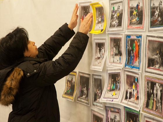 Visitor taping colored-in print-out of museum painting onto wall alongside other coloring sheets Visitor taping colored-in print-out of museum painting onto wall alongside other coloring sheets