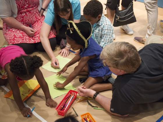 Children drawing on colored paper while adults supervise Children drawing on colored paper while adults supervise