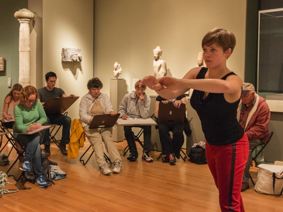 Visitors sitting on foldable chairs in gallery sketch model standing with arms reaching forward Visitors sitting on foldable chairs in gallery sketch model standing with arms reaching forward