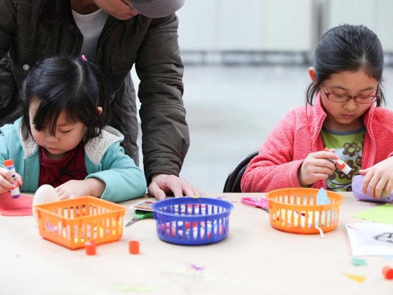 Two young visitors applying glue to construction paper with gluesticks Two young visitors applying glue to construction paper with gluesticks
