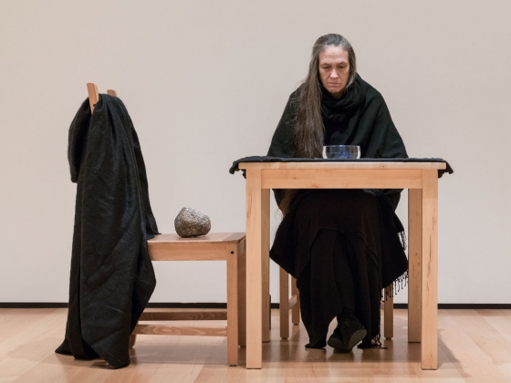 Marilyn Arsem: 100 Ways to Consider Time Marilyn performing during her exhibition, sitting at table and looking at glass bowl