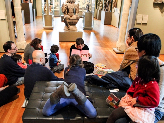 Story Hour, Nowruz 2015 Kids and parents in a gallery sitting around storyteller with book open