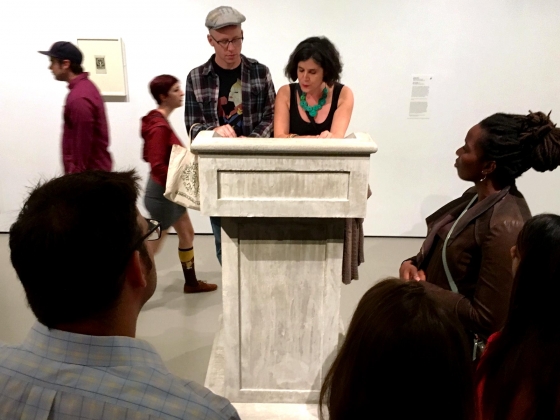 Amelia Pica: Now Speak!, couple at lectern as watches on