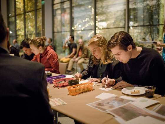 Two visitors sketching at art making table at First Friday event in Shapiro Family Courtyard