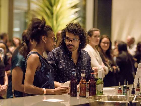 Two visitors standing at bar during First Friday event in Shapiro Family Courtyard
